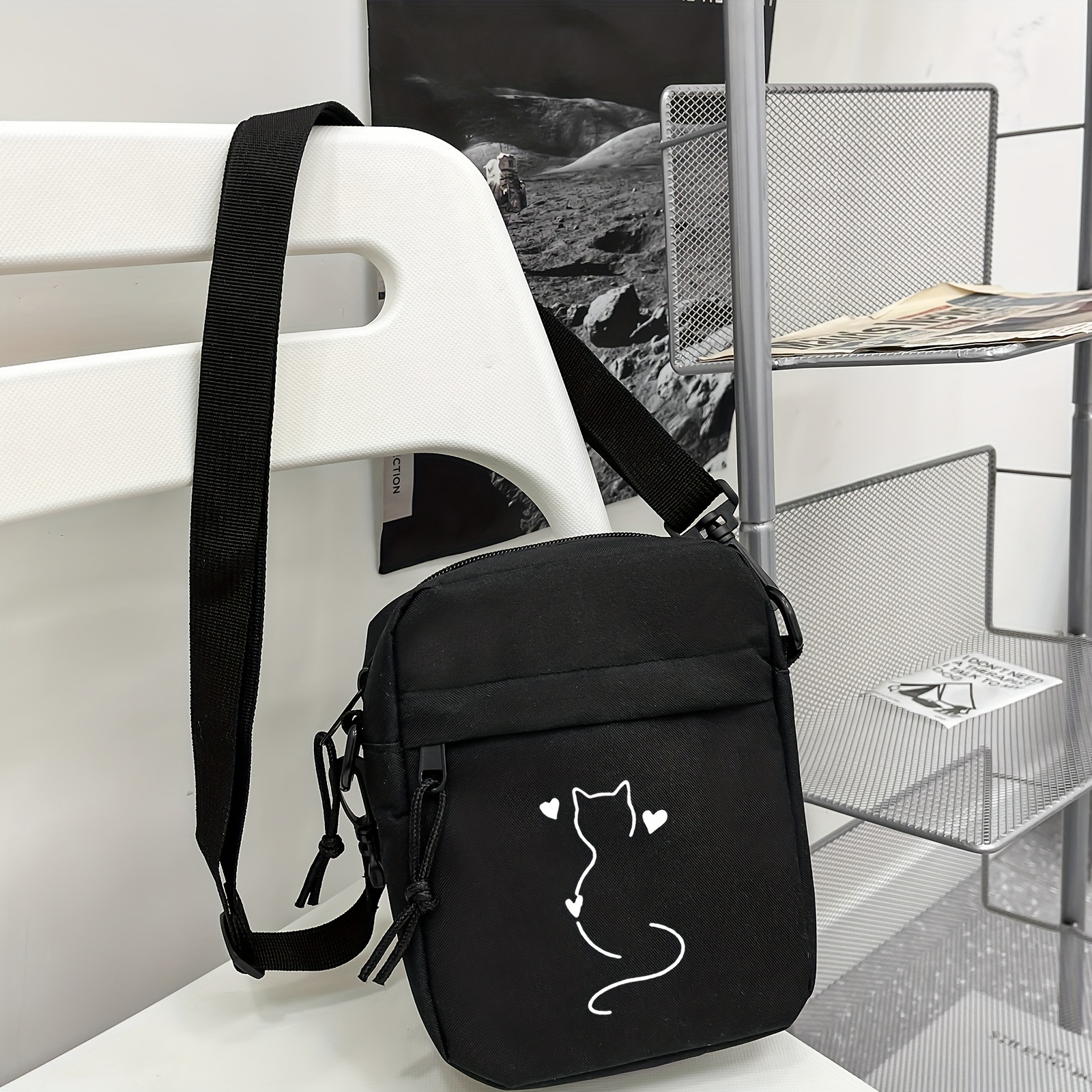 a stylish and minimalist black crossbody bag featuring a small cat and heart   for   occasions and can   serve as a multifunctional phone bag