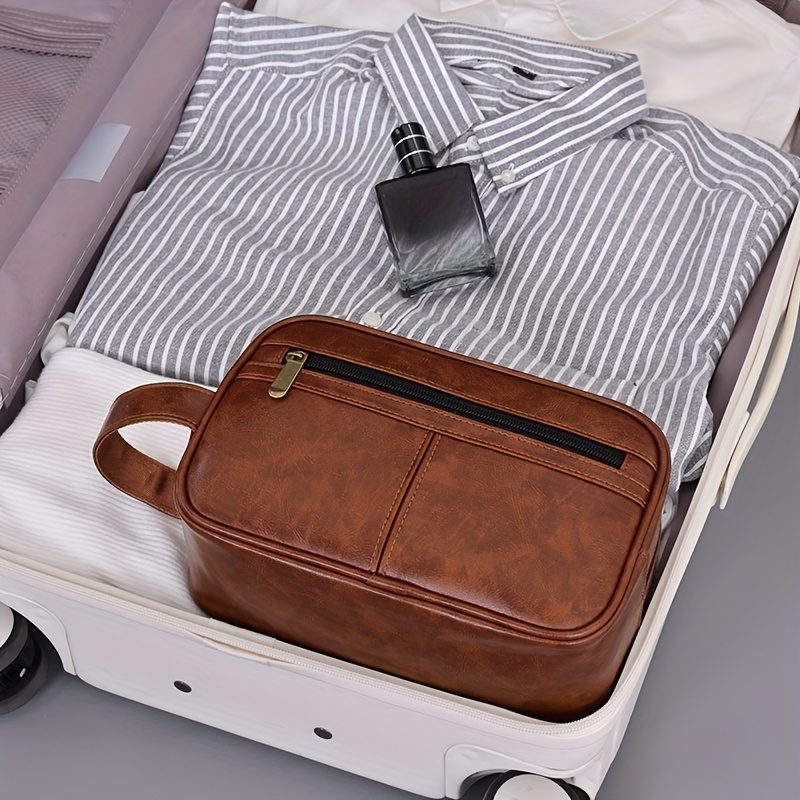A  brown leather toiletry bag packed in a luggage and sold by 100 Spartans.