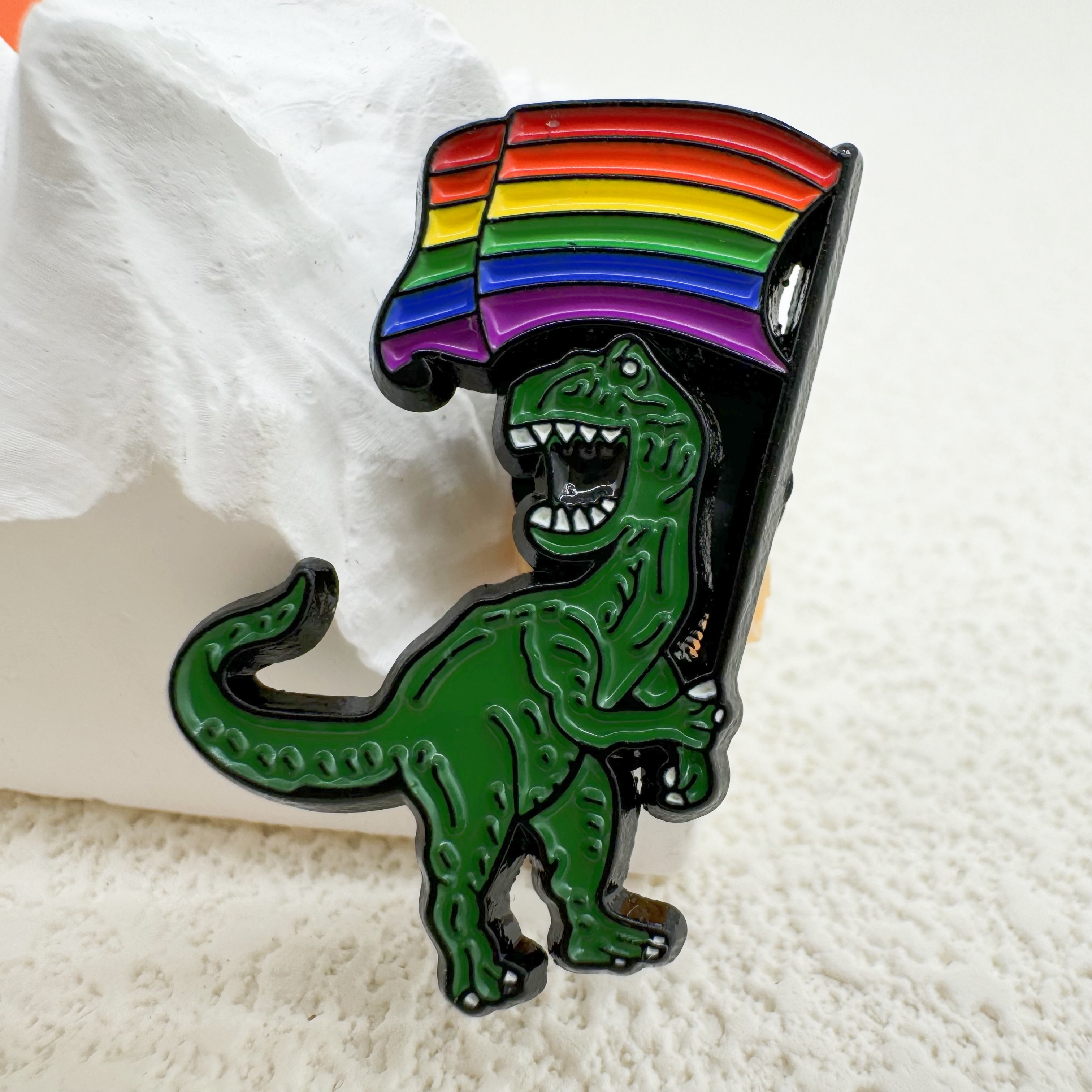 A Cartoon Dinosaur Flag Pin That Used As An Accessory For Backpacks, Clothing, Hats, And Badges