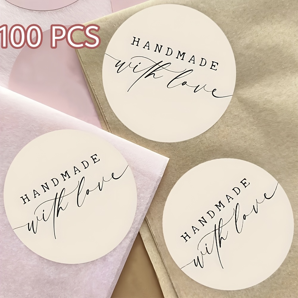 E-shop Ein Set aus 100 runden Aufklebern mit dem Spruch "Handgefertigt mit Liebe", hergestellt aus weißem, selbstklebendem Papier, ideal zum Dekorieren