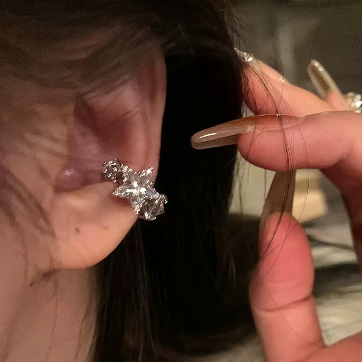 

Une pince d'oreille en cuivre argenté avec un design d' en synthétique. Ce bijou unique, de , est oreilles percées.