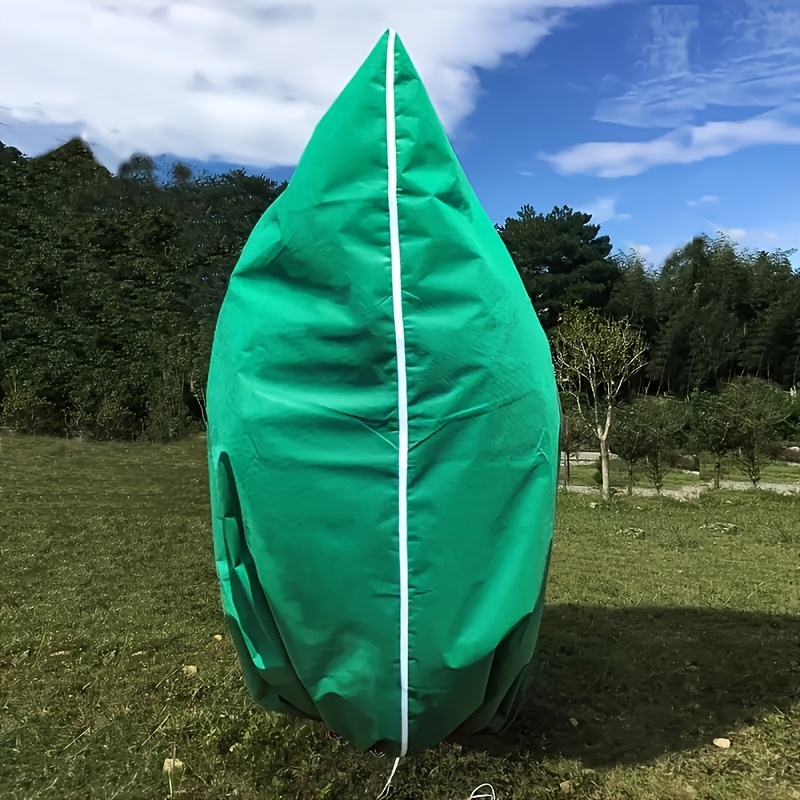 Green Outdoor Plant Cover For Winter Protection, Featuring A Zipper And Drawstring Bag. It Safeguards Trees And Shrubs From Frost And Snow, Providing And With Its Soft