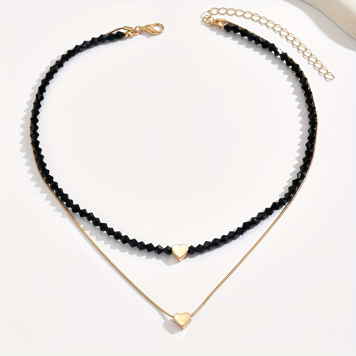 E-shop Eine stilvolle und minimalistische Herzanhänger-Halskette für Damen, mit glänzenden schwarzen Perlen und einem doppellagigen Design, für den ,