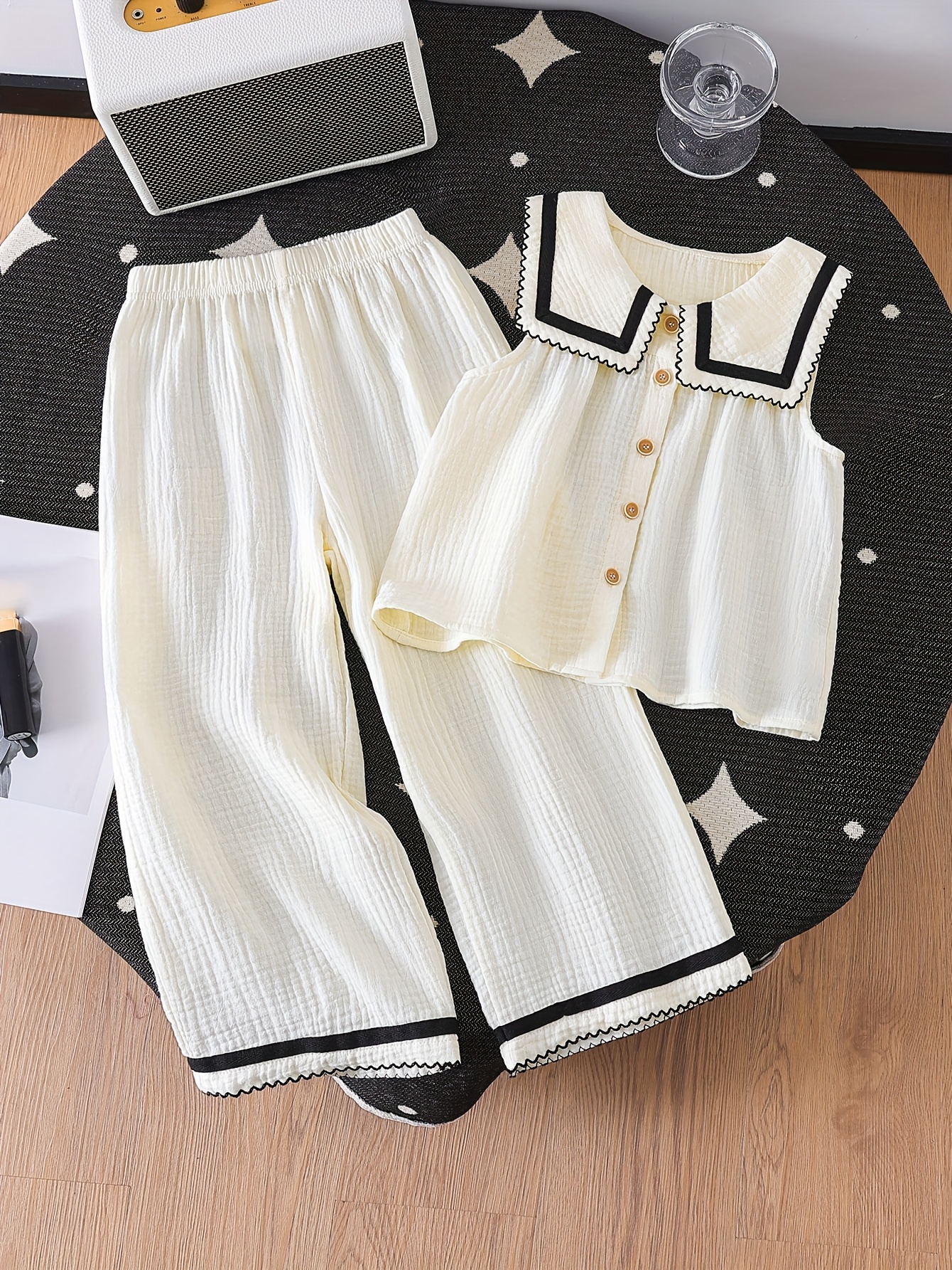 A Stylish New Collection for Girls in Spring And Summer Featuring Elegant And Versatile Designs. The Sleeveless Top Is Made from Quality Fabric with a Large Collar, Adorned with Wood Grain Buttons And Delicate Wave-Edged Ribbon Details. It Pairs Perfectly with Long Pants That Have Matching Wave-Edged Ribbon Accents, Making It a Comfortable Two-Piece Set for Casual Outings And Gatherings. an Exquisite Gift for Friends And Family, for Outdoor