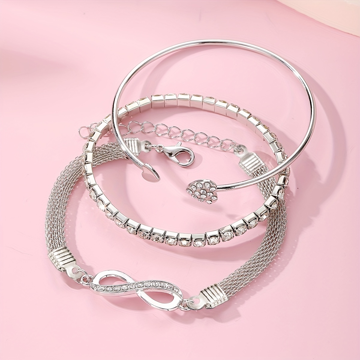 A Set of Three Women'S Bracelets And Bangles Featuring Wireless Symbols And Heart Designs Adorned with Rhinestones.