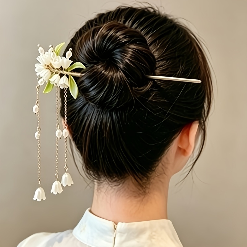 アイテム画像 【商品名】  ヘアピン。乳白色のリリー・オブ・ザ・ヴァレーの花束が咲き始め、透明な花びらと 緑の葉が組み合わさり、朝露から摘んだばかりのような新鮮さ。垂れ下がるパールチェーンは、足を踏むたびにやさしく揺れます。