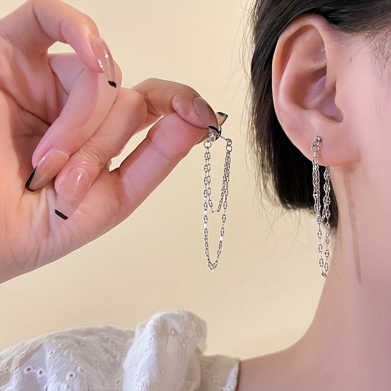 

Une paire de boucles d'oreilles minimalistes en acier inoxydable à double couche avec des pompons en chaîne pour femmes, présentant un intégré en chaîne.