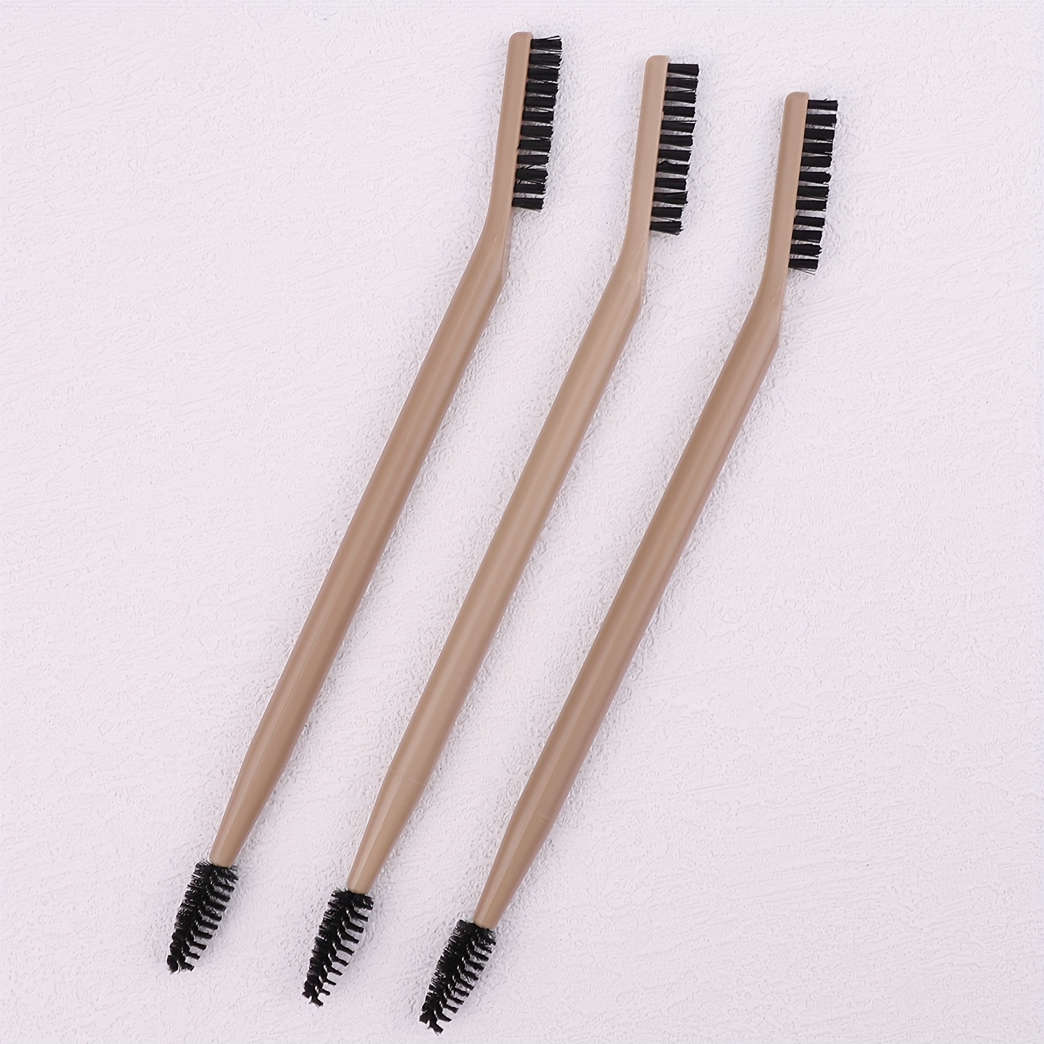 a set of 3 makeup brushes   in black white and multiple colors featuring a double ended lash brush eyebrow brush and comb