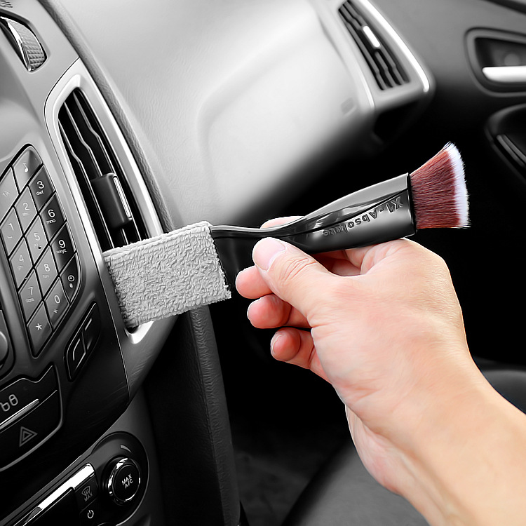 Trabajador con cepillo limpia la rejilla del conducto de aire del coche,  limpieza en seco y detallado.