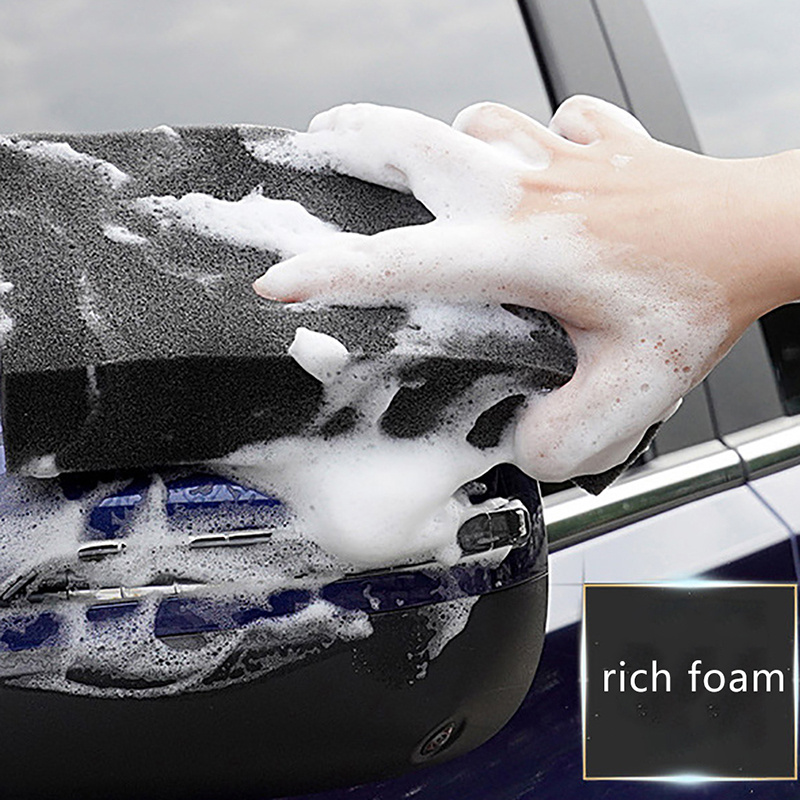 mans mano sujetando una esponja para lavar el coche. auto negro