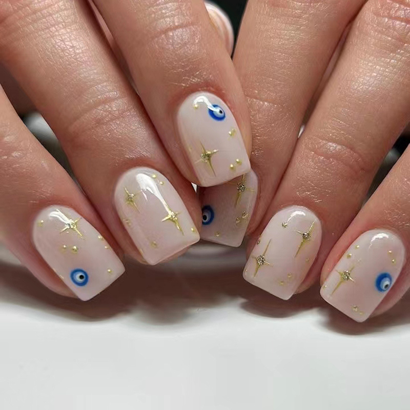 

Ensemble de 24 faux ongles carrés à pression courte avec un mauvais œil bleu et des étoiles dorées, Nail art brillant inspiré de l'an 2000, Formes d'ongles amovibles et prêtes à porter.