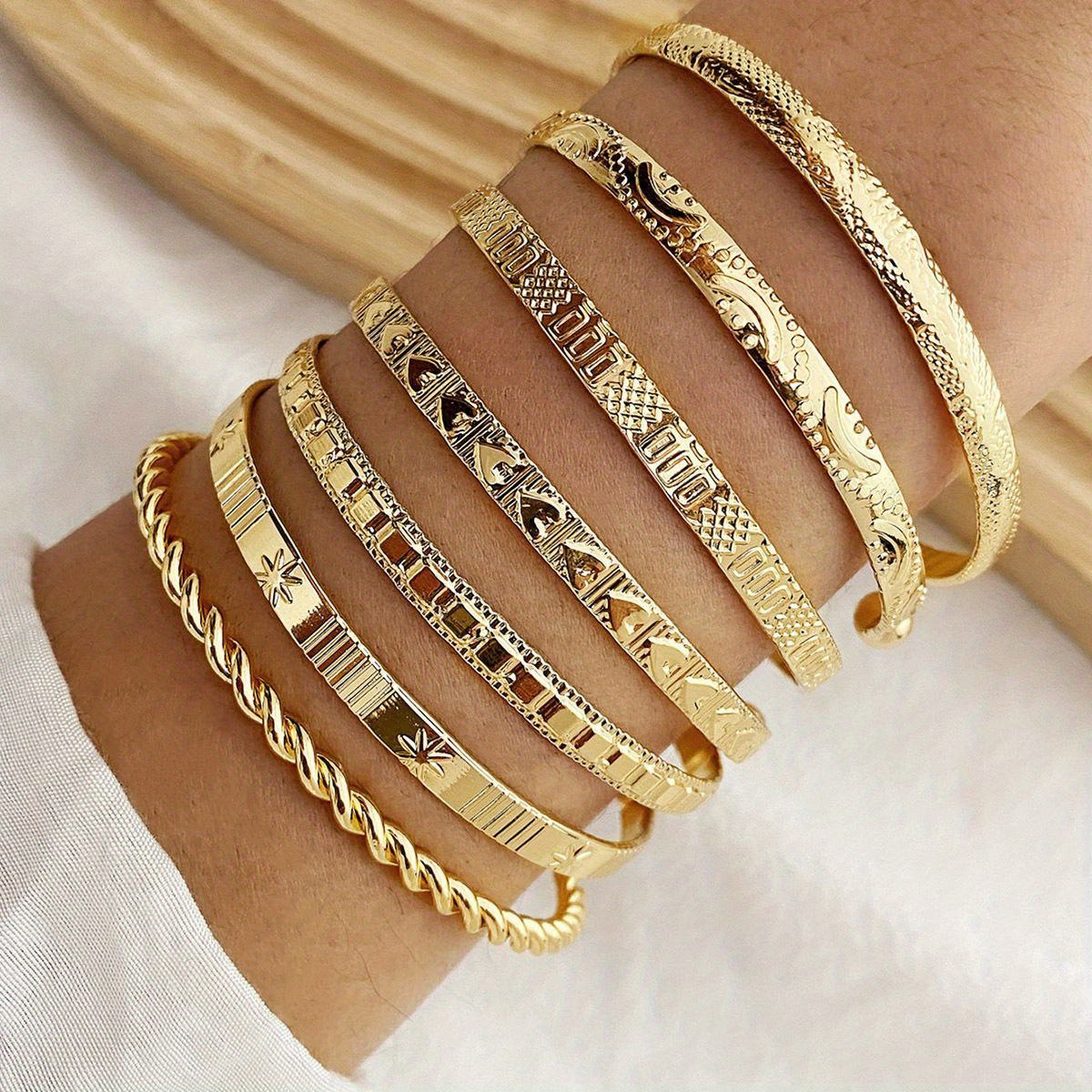 Set mit 7 goldfarbenen Armbändern – offene Armreifen im Boho- und Punk-Stil aus einer Legierung mit Pfeil- und Sternmuster für Alltag und Party. Produktdetails 0