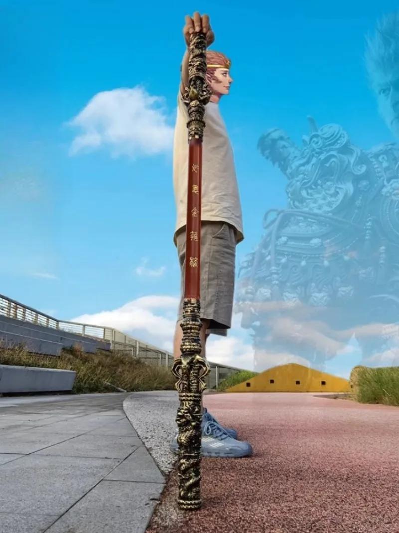 Person holding a very long Sun Wukong Stick against a blue sky with clouds.