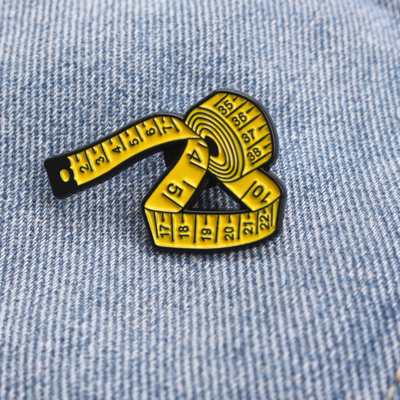 Enamel Pin Shaped Like A Yellow Tape Measure Featuring Detailed Scales, Combining Functionality And Style, An Ideal Present For Tailors, Seamstresses, And Craft Lovers