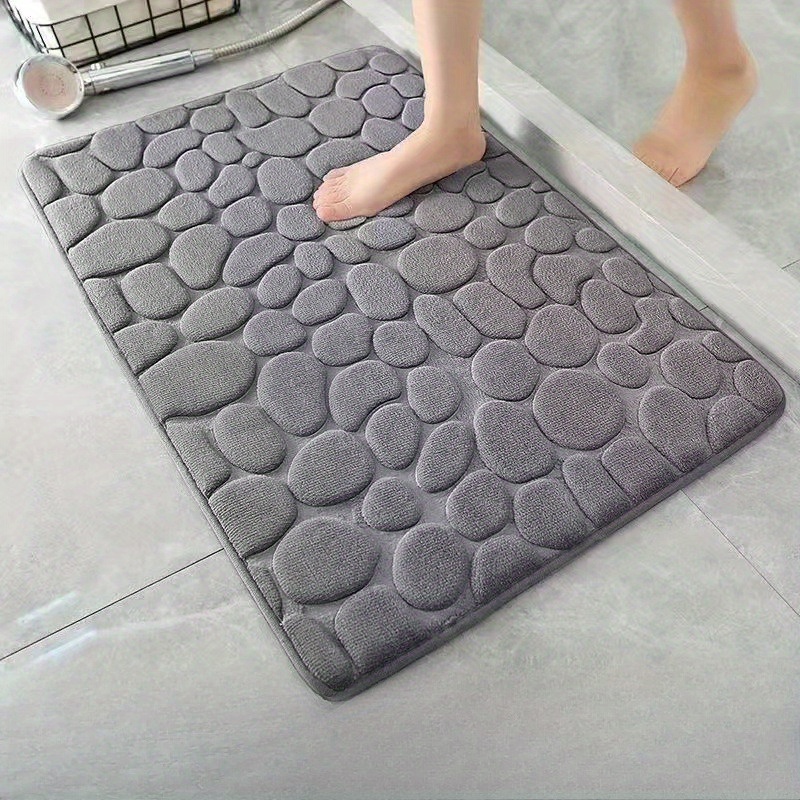 

Une pièce de tapis de sol absorbant pour , avec un design de galets sur un fond blanc, fabriqué en et conçu pour ne pas glisser, à utiliser dans les de bain.