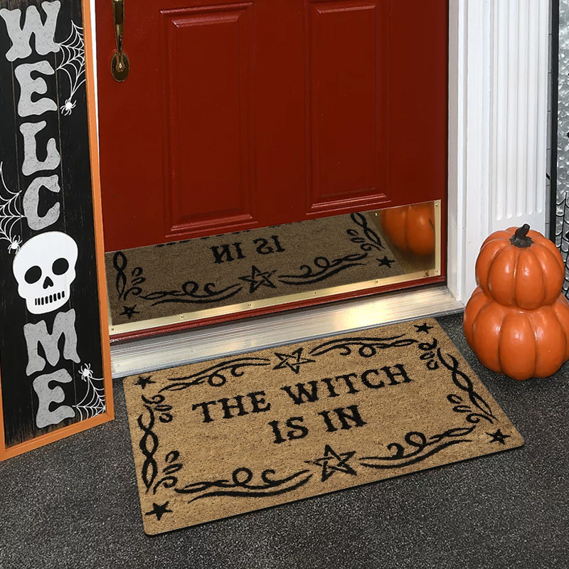 Image of A Magical Doormat Featuring 'the Witch Is In', Made Of Plush Material With A Thickness Of 0.4 Inches And Weighing 580 Grams. It Has A Brown Base With A Black Star And Spell Design, For Halloween