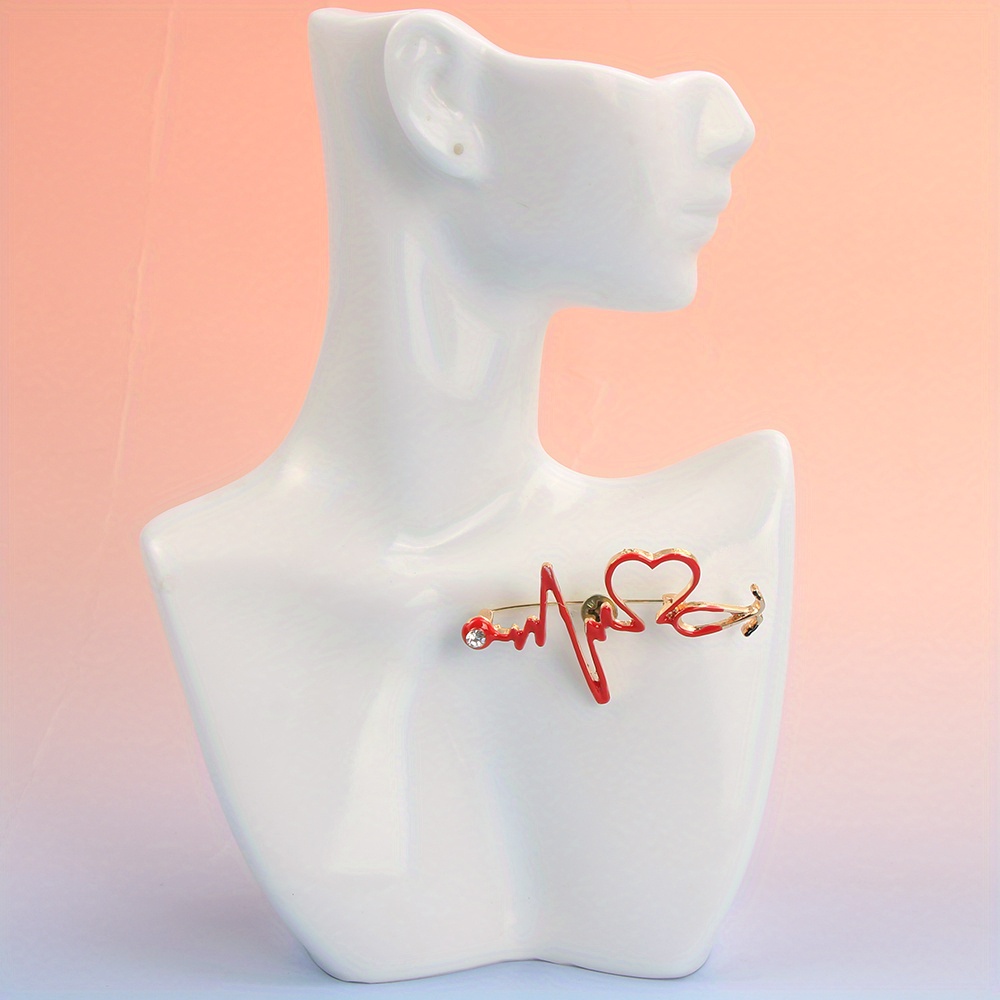 A Stylish Brooch Shaped Like A Stethoscope, Featuring A Red Hue And Rhinestones, Perfect For Accessorizing