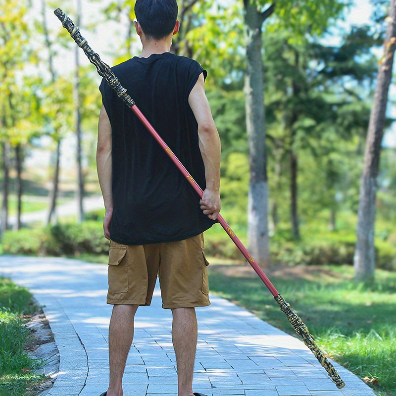 Person holding a long spear-like Sun Wukong Stick in a park setting