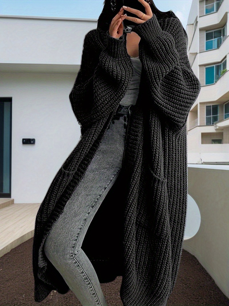 A lady wearing a black oversized knitted coat with pockets sold by 100 Spartans