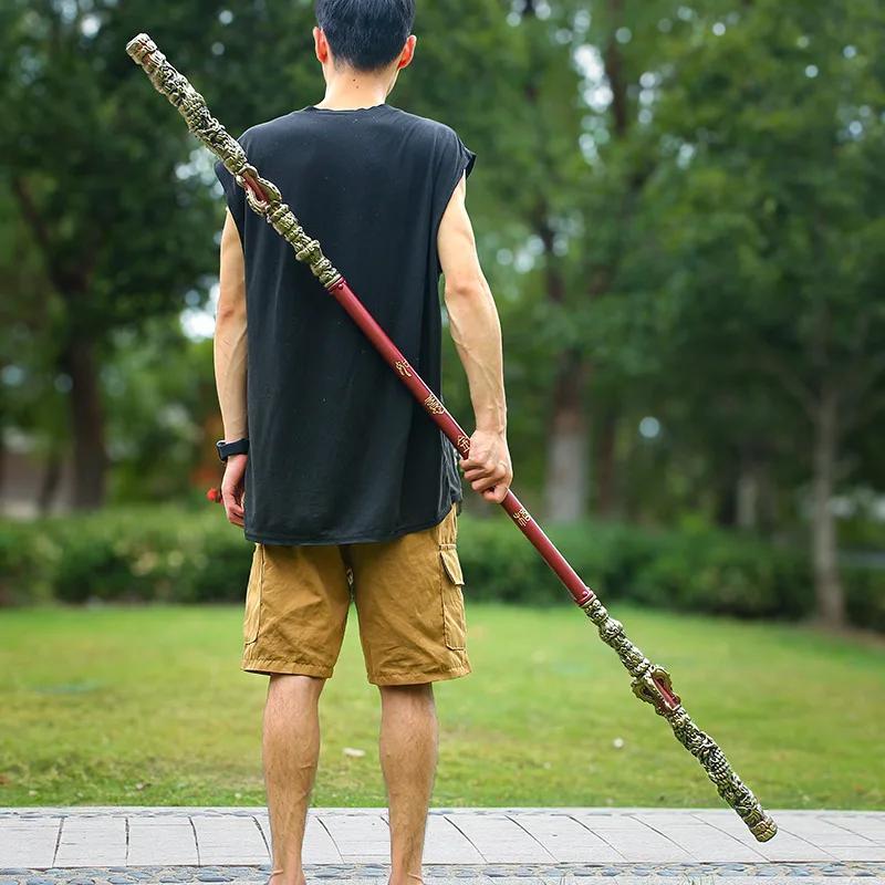 Person holding a long Sun Wukong Stick  in a park setting